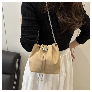 Détail du sac seau beige avec texture crocodile, fermoir papillon argenté et perles