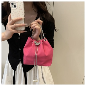 Detail of pink croc-textured bucket bag with silver butterfly clasp and pearl chain