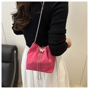 Detail view of pink pleated bucket bag with butterfly hardware and silver chain strap
