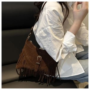 Detail of dark brown suede shoulder bag with long fringes and vintage metal buckle
