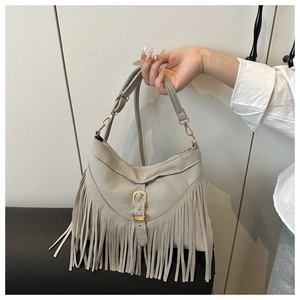Close-up of light grey suede tassel shoulder bag with golden metallic pin buckle detail