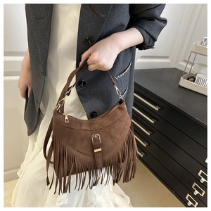 Close-up of brown suede hobo bag featuring retro metal buckle and fringe details