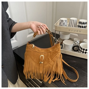 Detail of a brown faux suede handbag featuring long fringe and a metallic buckle strap