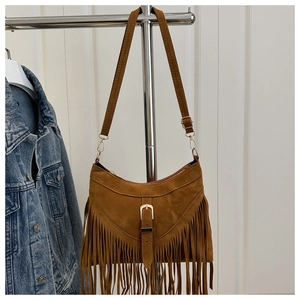 Detail of brown suede crossbody bag with long fringes and decorative buckle on hanger