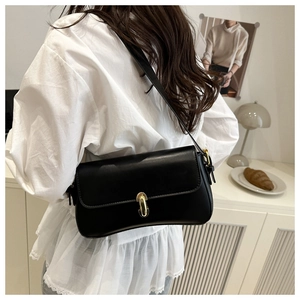 Detail of elegant black leather underarm bag with gold metal buckle and adjustable strap