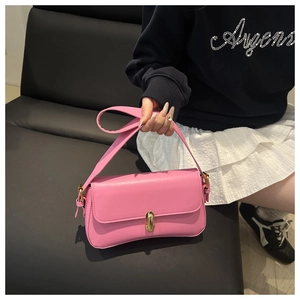 Detail shot of the pink leather underarm bag featuring a refined gold metal twist lock