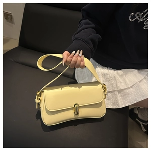 Detail of pale yellow shoulder bag featuring golden metallic buckle and smooth texture
