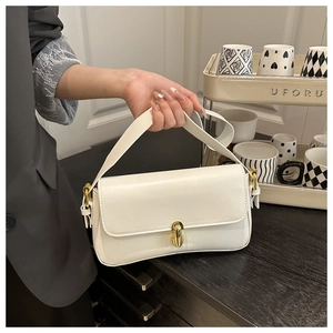 Close-up of white leather underarm bag with elegant gold twist lock and fine texture