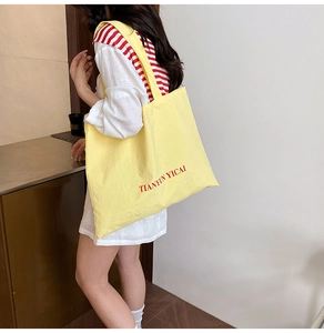 Détail du cabas en toile jaune avec lettres rouges imprimées et bandoulière spacieuse