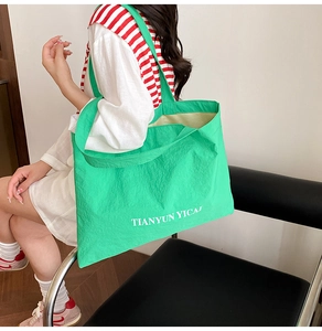 Gros plan sur le fourre-tout en nylon vert vif avec imprimé blanc sur haut rayé
