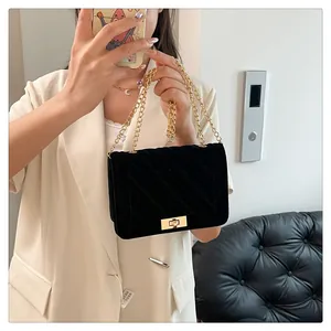 Détail du sac à bandoulière en velours noir avec chaîne dorée et fermoir pivotant