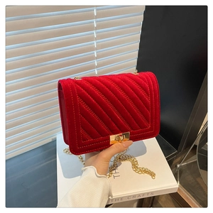 Détail du sac à bandoulière en velours rouge avec texture matelassée en V