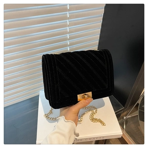 Détail du sac bandoulière en velours noir avec chaîne dorée et texture matelassée