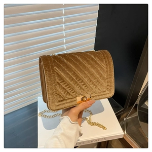 Détail d'un sac bandoulière en velours marron avec matelassage en V et chaîne dorée