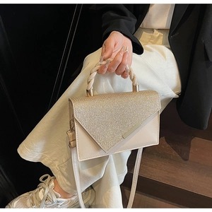 Detail of cream crossbody bag featuring glitter envelope flap and golden hardware accents