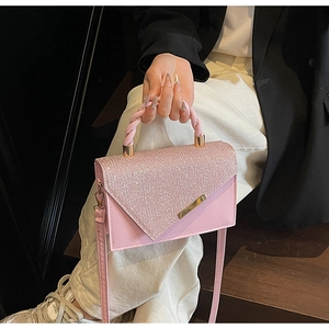 Detailed view of pink glitter crossbody bag with twisted handle and gold hardware