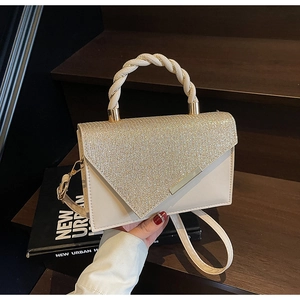 Detail of elegant cream shoulder bag featuring gold glitter flap and braided handle texture