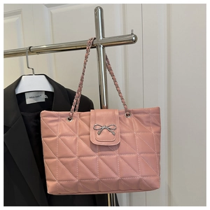 Detailed view of pink quilted leather shoulder bag with silver bow clasp and chain strap