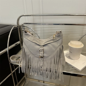 Light gray fringe shoulder bag in matte suede with golden buckle on a display stand