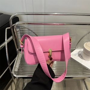 Bright pink minimalist underarm bag with gold metal clasp shown in a lifestyle setting