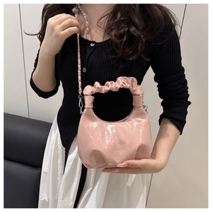 Detail of light pink cloud bag featuring pleated handles and glossy patent leather finish