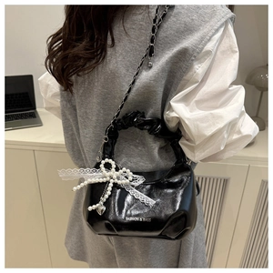 Detail of black pleated handbag with pearl bow and Fashion & Bags printed text