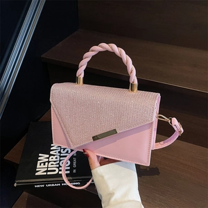 Pink shoulder bag with gold thread embroidery and glitter V-cut flap on dark wooden steps