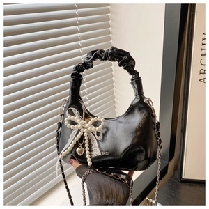 Detail of black crescent bag with pearl beads, lace bow, and heart pendant charm
