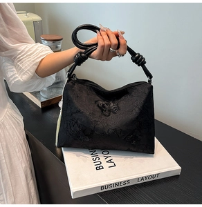 Close-up of black tote bag featuring butterfly embroidery and yellow tassel charm