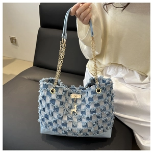 Détail du sac cabas en denim bleu avec motif à franges et pendentif élan élégant