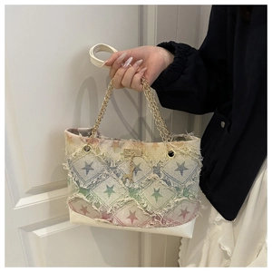 Détail d'un sac en toile dégradé arc-en-ciel avec chaînes dorées et pendentif cerf