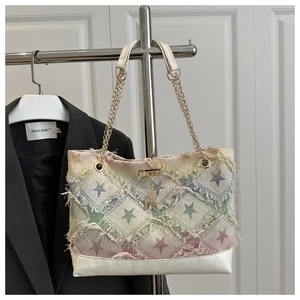 Detail of star-patterned denim handbag with frayed edges and metallic deer charm accessory