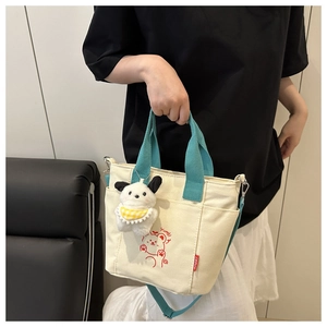 Detail of off-white canvas tote bag with red cartoon bear and plush dog charm