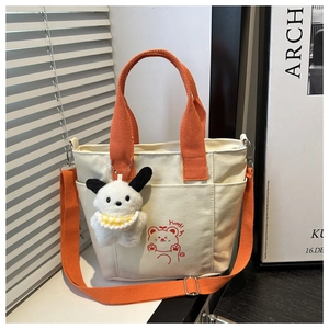 Detail of canvas bag with orange straps, cute cartoon bear print and plush dog pendant