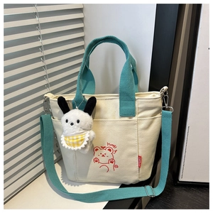 Detail of canvas tote bag featuring blue handles and a cute cartoon bear print