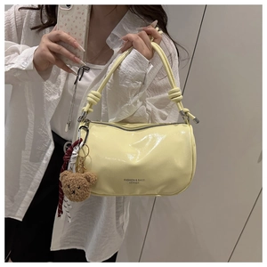 Detail of light yellow patent leather shoulder bag with knot handle and bear charm