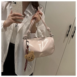 Detail of pink cylindrical shoulder bag with glossy finish and cute brown bear charm
