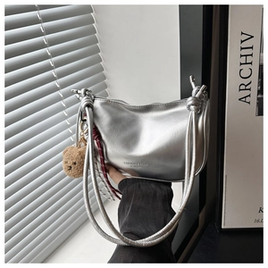 Detailed shot of silver dumpling bag with knot handle and plush bear charm