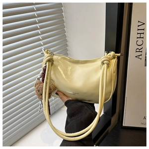 Close-up of light yellow hobo bag with knotted handle and cute brown bear pendant