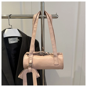 Detailed view of pink cylindrical shoulder bag with decorative bow and silver zipper