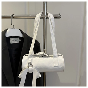 Close-up of a white cylindrical shoulder bag with large bow detail on a hanger