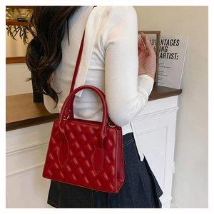 Detailed side view of a red quilted leather handbag worn by a model in a luxury interior