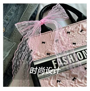 Close-up of pink tote bag with black bow patterns and FASHION decorative band detail