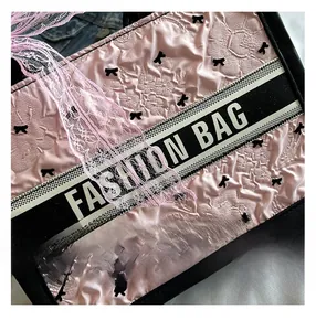 Close-up of pink embossed texture fabric with black bow pattern and fashion bag detail