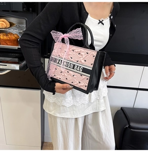 Close-up of pink quilted tote bag with silk scarf bow and black embroidered accents