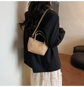 Detail showing the lychee grain texture and top handles of this beige bucket bag for women