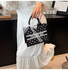 Detail of fashion tote bag with white lace bow and printed text ribbon decoration