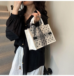 Detail of white tote bag with black bow patterns, lace ribbon, and Fashion Bag text