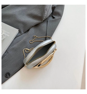 Detail of silver oval evening bag with gold metal handle and interior compartment view