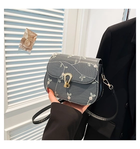 Gros plan du sac bandoulière gris avec broderie florale et fermoir en métal doré